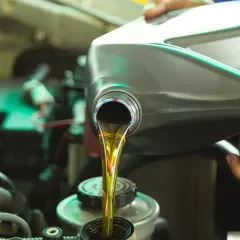 Mechanik nalewa olej silnikowy do silnika. Czy przy wymianie rozrządu wymienia się olej? Tak, to dobry moment na wymianę płynów.