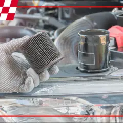 Ręka w rękawicy trzyma zużyty filtr oleju, na którym widać drobne srebrne opiłki w oleju. Obok stoi nowy filtr.