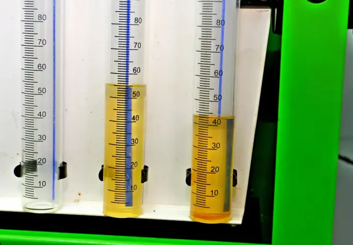 Trzy menzurki z podziałką. W dwóch widoczny żółty płyn, prawdopodobnie paliwo w oleju diesel, na poziomie ok. 50 i 40 ml.