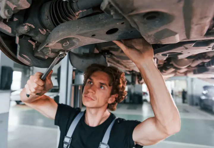 Mechanik naprawia zawieszenie auta, podejrzewając jazdę z uszkodzoną tuleją wahacza.