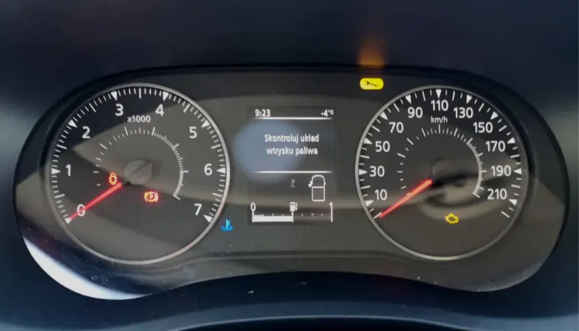 Na desce rozdzielczej Renault świeci się kontrolka "Skontroluj układ wtrysku paliwa". Obok widać wskaźniki prędkości i obrotów.