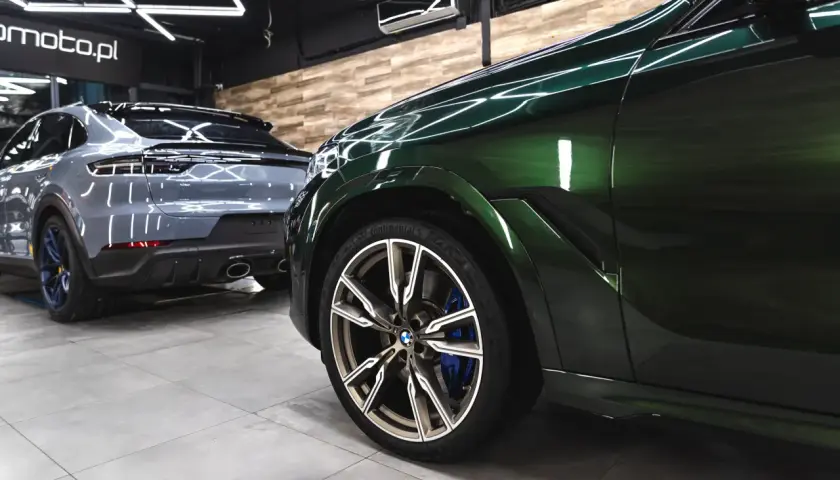 Błyszczące, zielone BMW i szare Porsche w garażu. Detailing co to? To dbałość o każdy szczegół tych luksusowych aut.