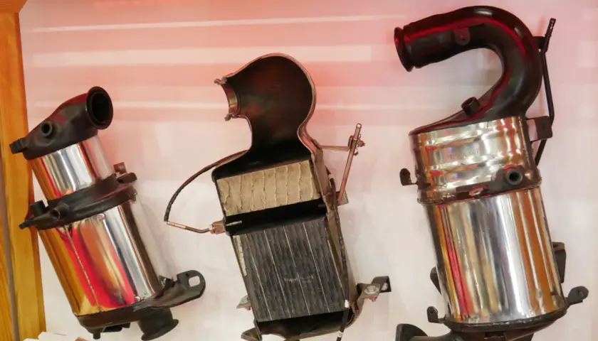 Trzy części samochodowego katalizatora, pokazujące jego budowę: metalową obudowę i ceramiczny wkład.