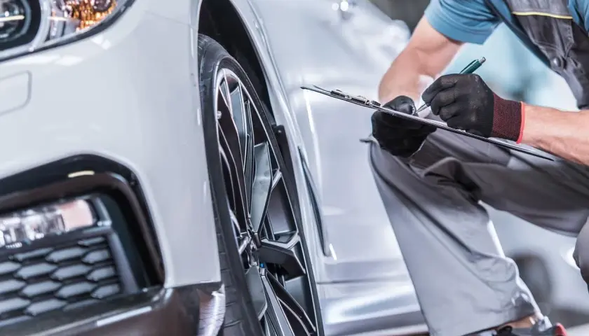 Mechanik w rękawiczkach sprawdza dokumenty przy nowym samochodzie. To część procesu, który określa, co to homologacja i czy pojazd spełnia normy.