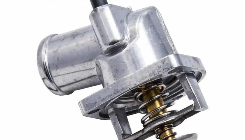 Metalowy termostat samochodowy z widocznym mechanizmem sprężynowym. Uszkodzony termostat może powodować problemy z temperaturą silnika.