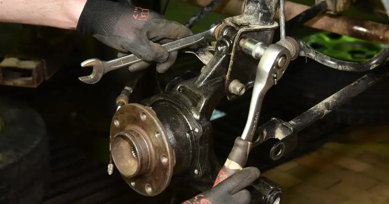 Mechanik dokręca śruby przy piaście. Huczące łożysko jak długo można jeździć? Lepiej wymienić od razu.