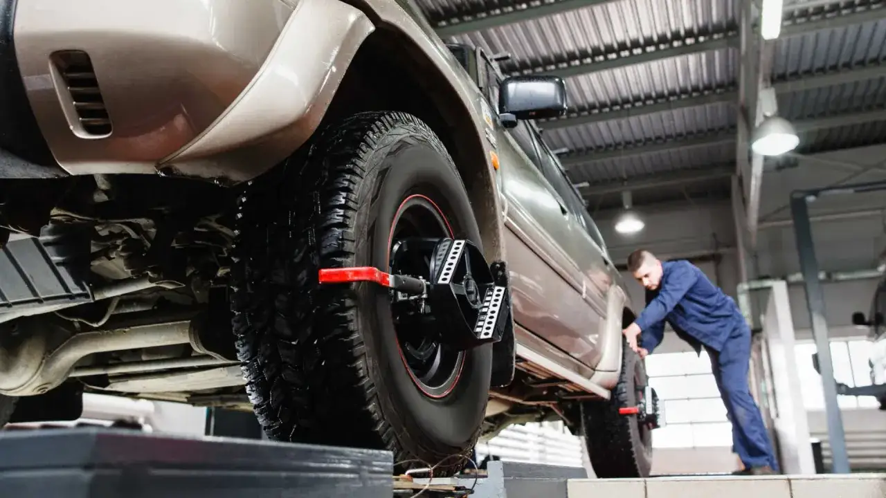 Mechanik sprawdza ustawienie kół, by prawidłowo ustawić zbieżność.